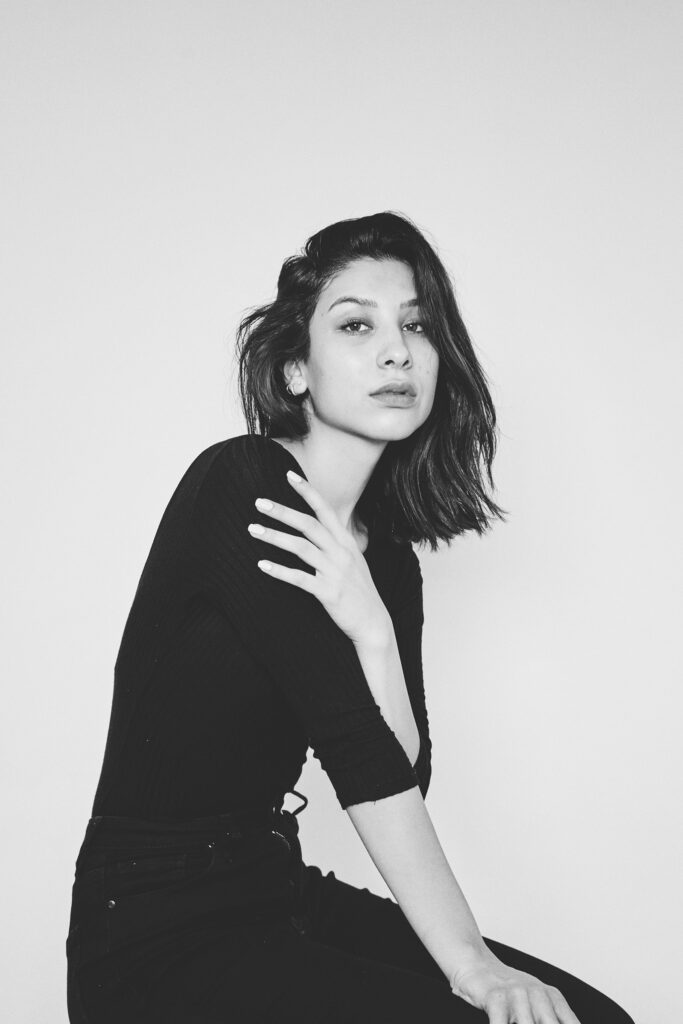 Nadya Inzunza is shown in a black and white portrait wearing a black top and black pants with her hand gently resting on her shoulder.